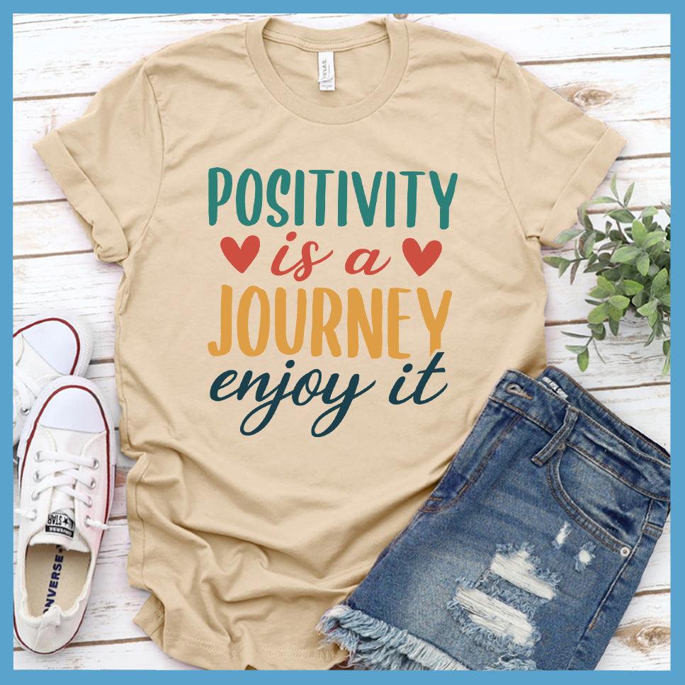 Positivity Is A Journey Enjoy It T-Shirt Colored Edition Soft Cream - Inspirational quote t-shirt with 'Positivity is a Journey Enjoy It' message.