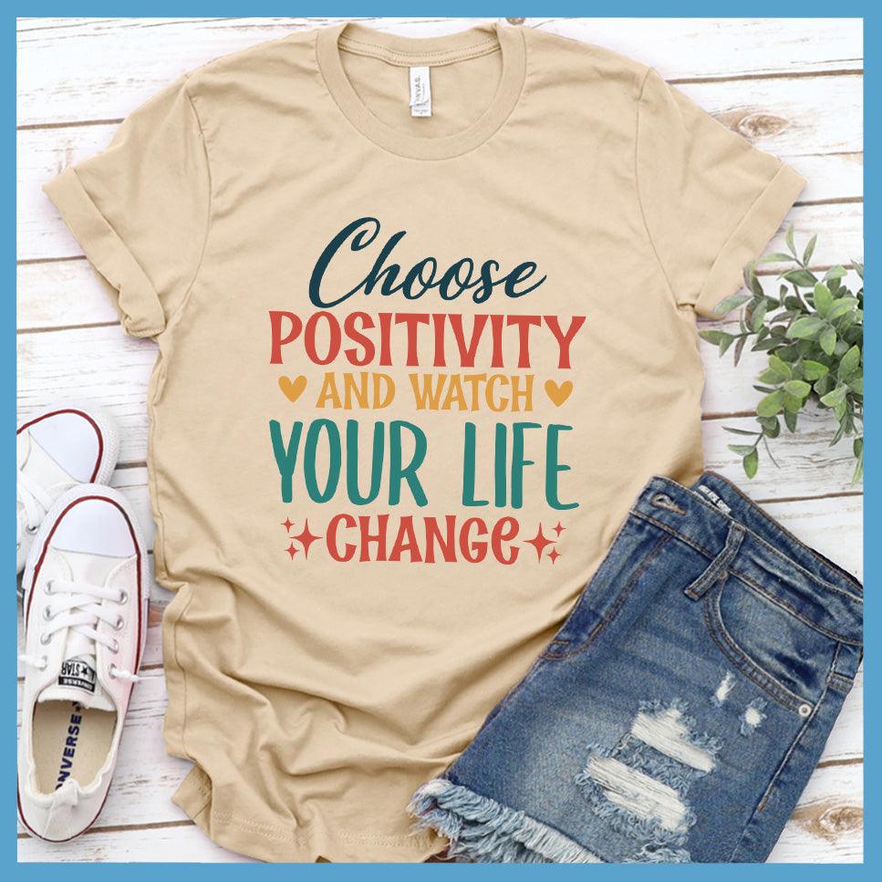 Choose Positivity And Watch T-Shirt Colored Edition Soft Cream - Inspirational Choose Positivity slogan t-shirt laid out with casual denim and sneakers