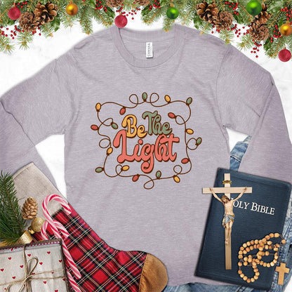 Be The Light Colored Edition Long Sleeves Storm - Inspiring 'Be The Light' design on a long sleeve tee with cozy holiday vibes.
