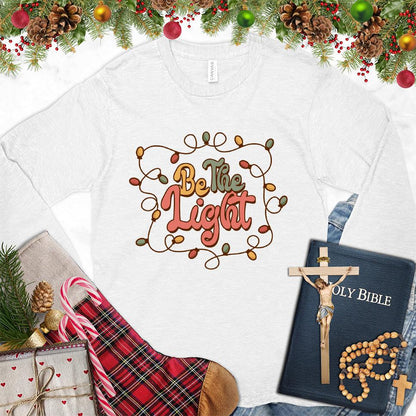 Be The Light Colored Edition Long Sleeves White - Inspiring 'Be The Light' design on a long sleeve tee with cozy holiday vibes.