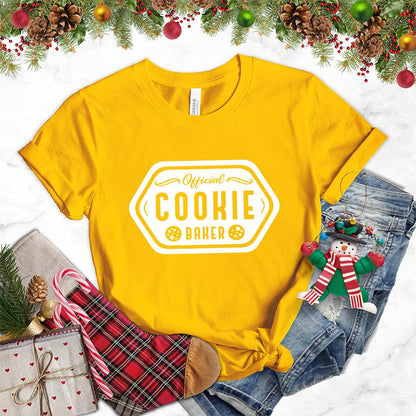 Official Cookie Baker T-Shirt Gold - Graphic tee with 'Official Cookie Baker' logo in a festive kitchen setting