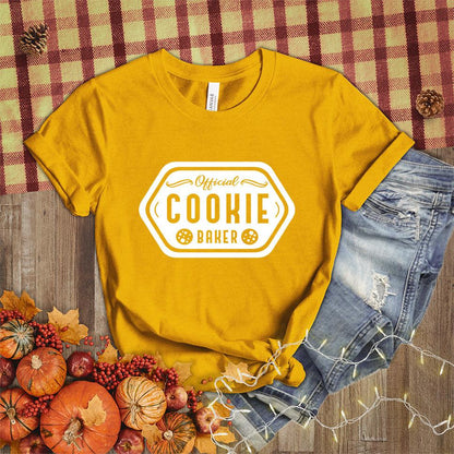 Official Cookie Baker T-Shirt Heather Mustard - Graphic tee with 'Official Cookie Baker' logo in a festive kitchen setting