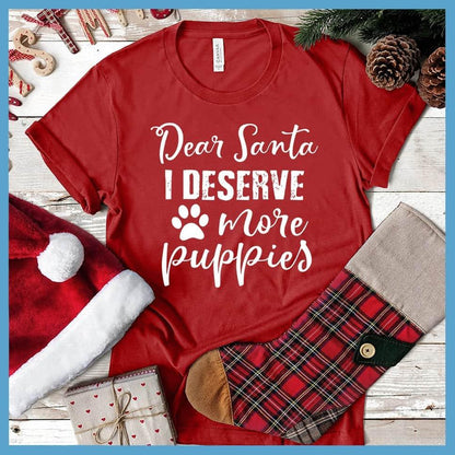 Dear Santa I Deserve More Puppies T-Shirt Canvas Red - Humorous holiday-themed T-shirt with 'Dear Santa I Deserve More Puppies' message in festive script.