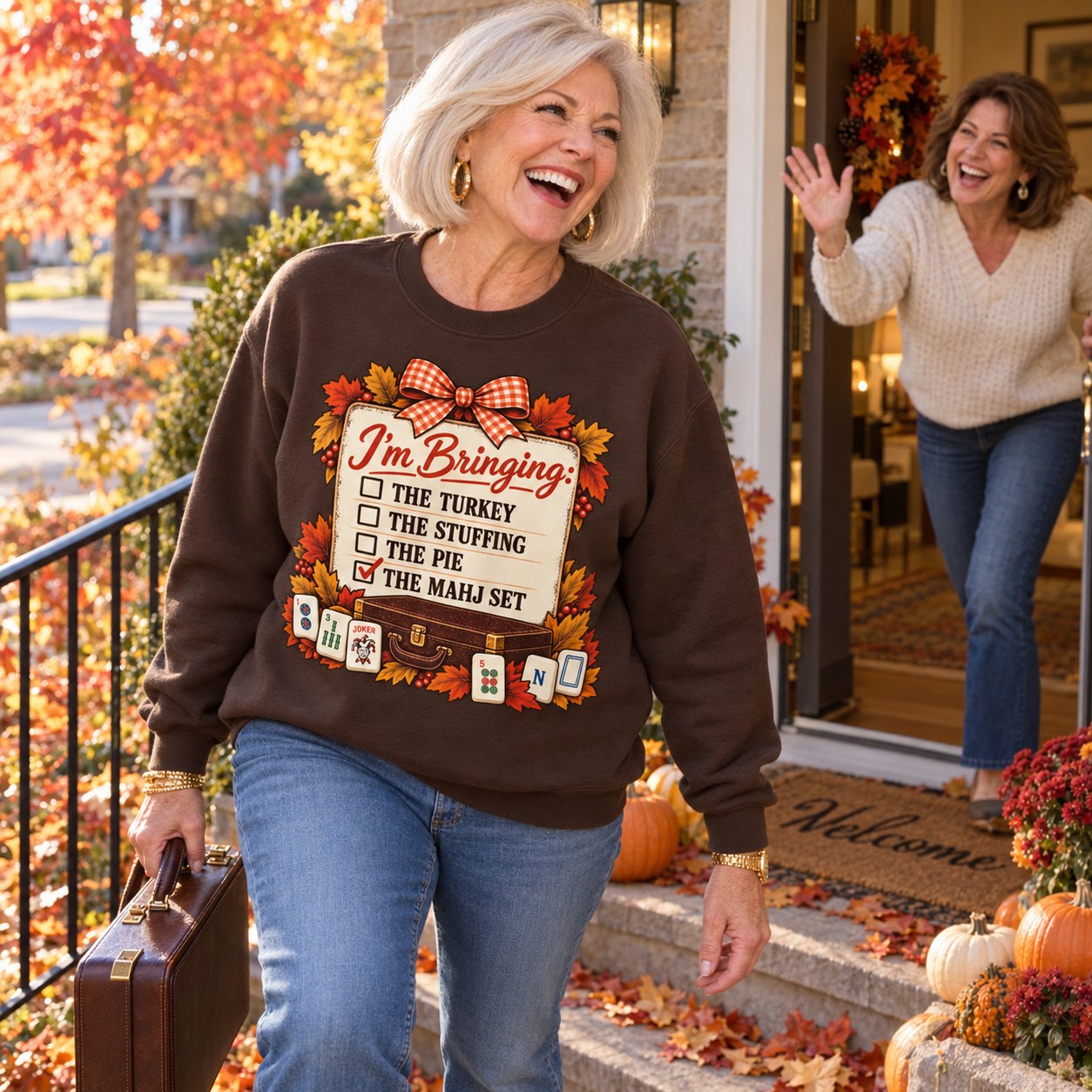 A woman carrying her mahjong case up a friend’s steps in fall in the Mahj Set sweatshirt