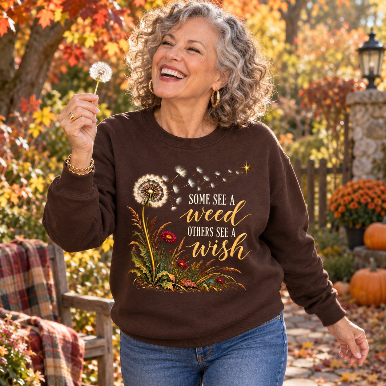 A woman holding a dandelion in an autumn garden in the Some See A Weed sweatshirt